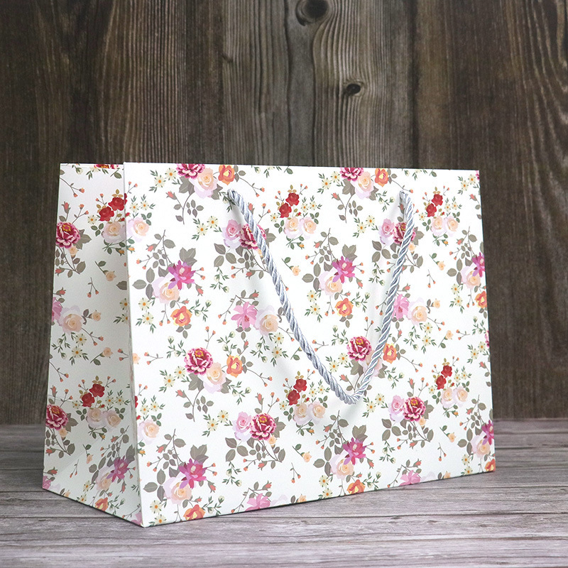 Wholesale minimalist floral-print paper bags  customizable with logos; small-sized shopping bags for gifts and souvenirs.