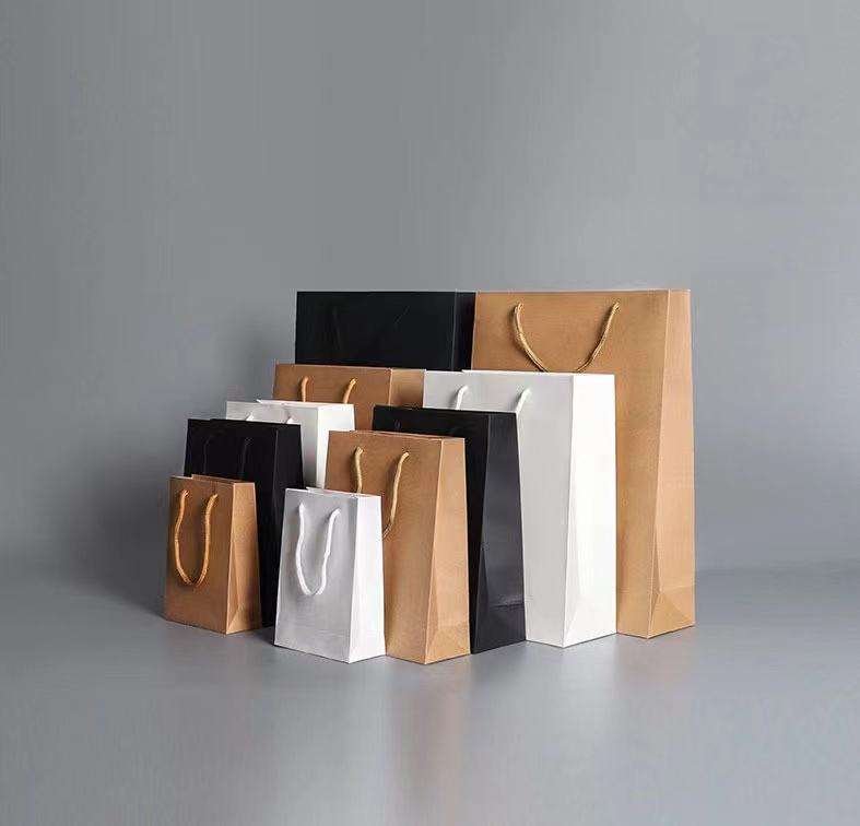 Factory-customized kraft paper bags with handles; color options available.